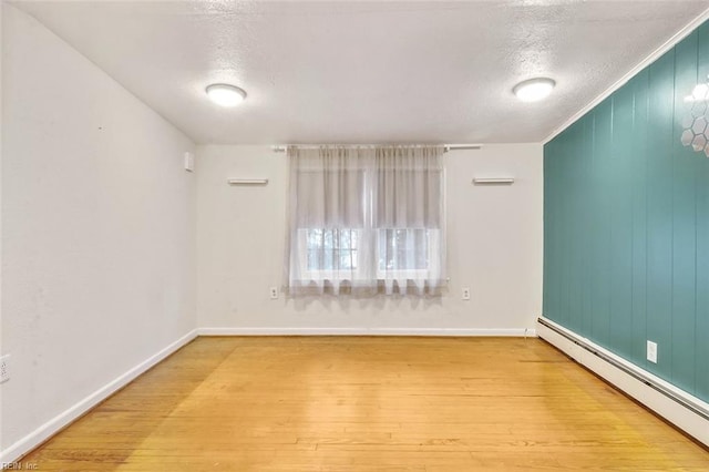 unfurnished room with hardwood / wood-style floors, a textured ceiling, and a baseboard heating unit