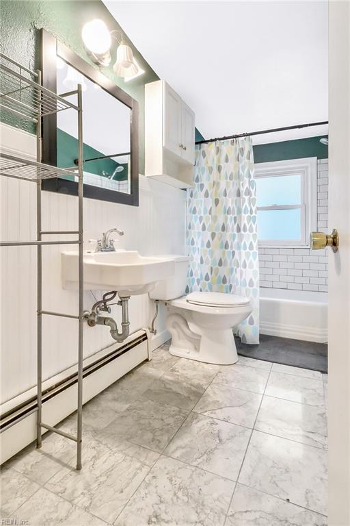 full bathroom featuring sink, shower / bath combo with shower curtain, a baseboard radiator, and toilet