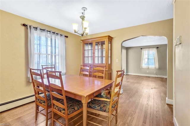 dining space with a wealth of natural light, light hardwood / wood-style flooring, and an inviting chandelier