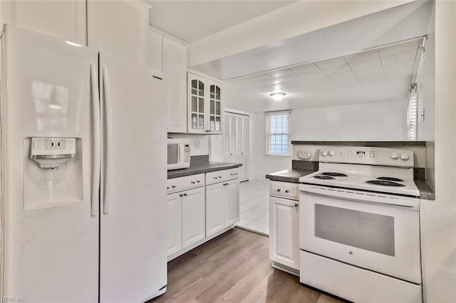 kitchen featuring white appliances, hardwood / wood-style flooring, and white cabinetry