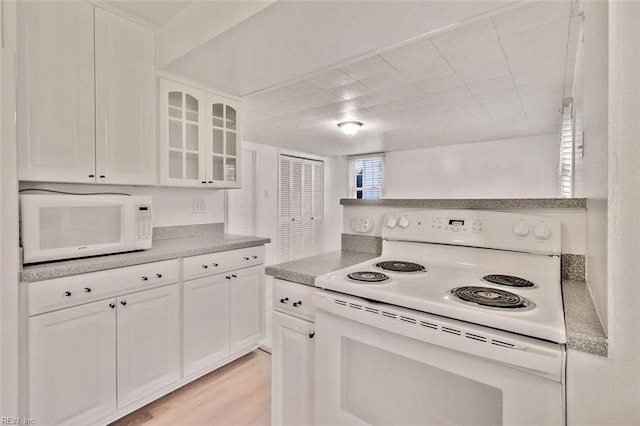 kitchen with white cabinetry, light wood-type flooring, and white appliances