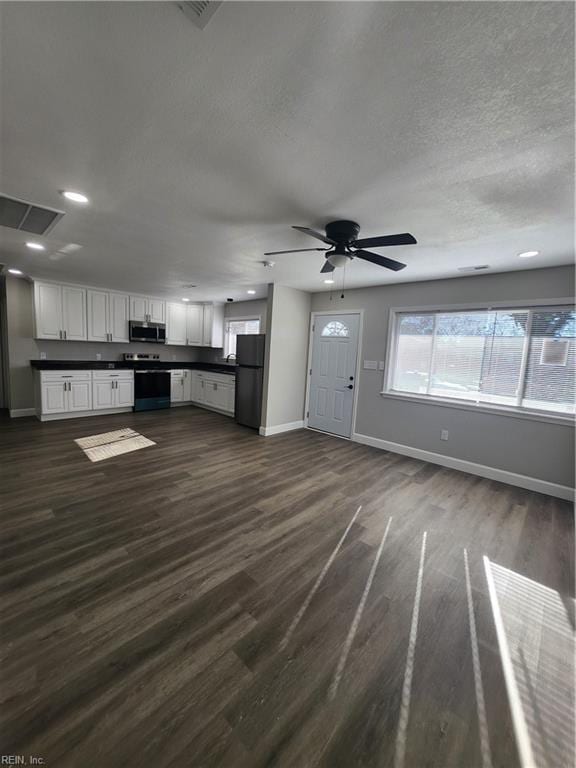 kitchen with white cabinets, appliances with stainless steel finishes, ceiling fan, and dark wood-type flooring