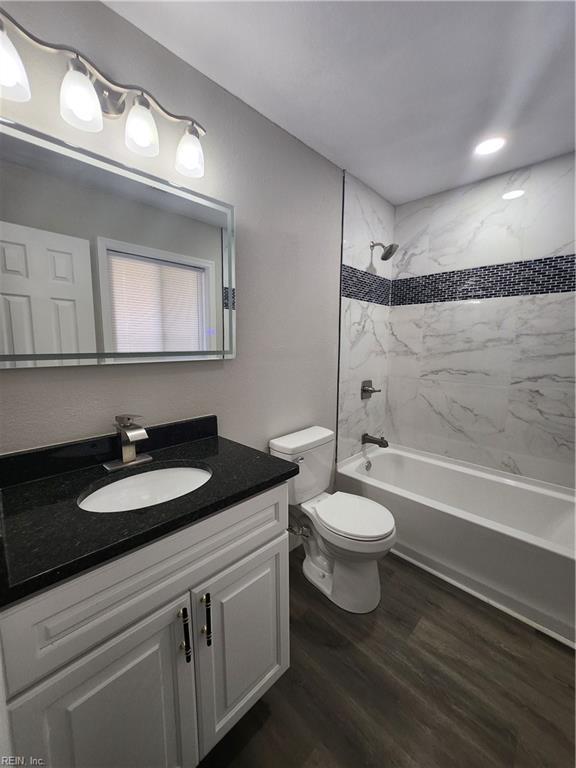 full bathroom with vanity, tiled shower / bath combo, hardwood / wood-style flooring, and toilet