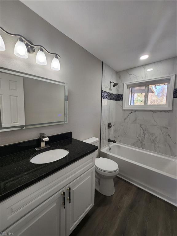 full bathroom featuring vanity, toilet, wood-type flooring, and tiled shower / bath