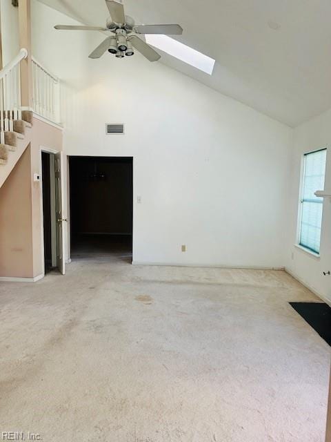 unfurnished living room with carpet flooring, ceiling fan, high vaulted ceiling, and a skylight