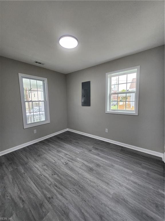 unfurnished room with electric panel and dark hardwood / wood-style flooring