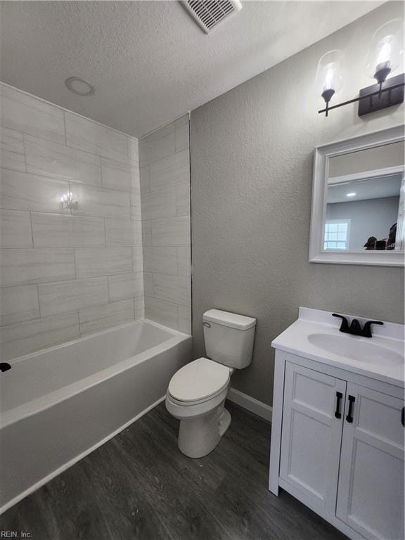 full bathroom with vanity, a textured ceiling, hardwood / wood-style flooring, toilet, and tiled shower / bath