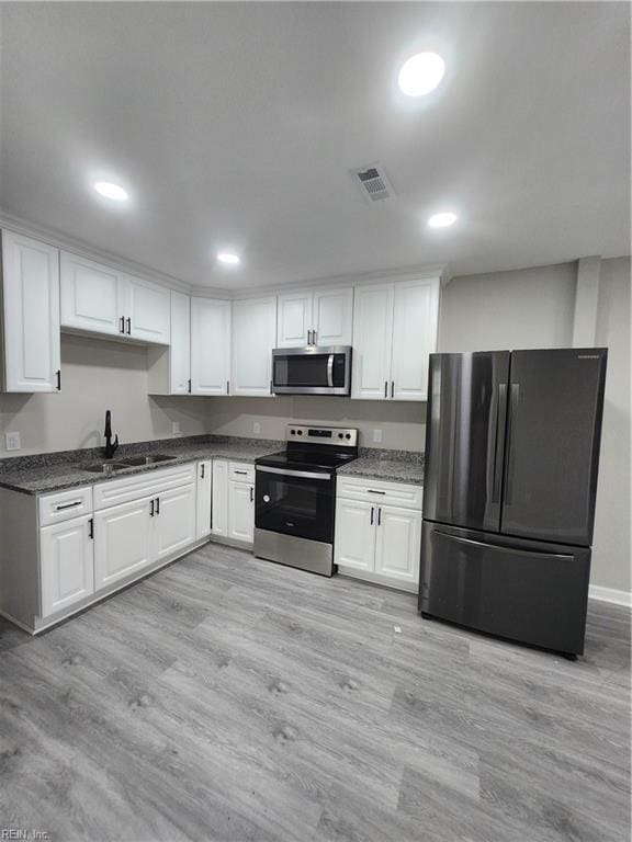 kitchen with white cabinets, light wood-type flooring, and stainless steel appliances