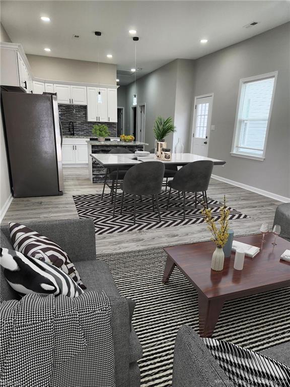 interior space featuring backsplash, stainless steel refrigerator, white cabinetry, and pendant lighting