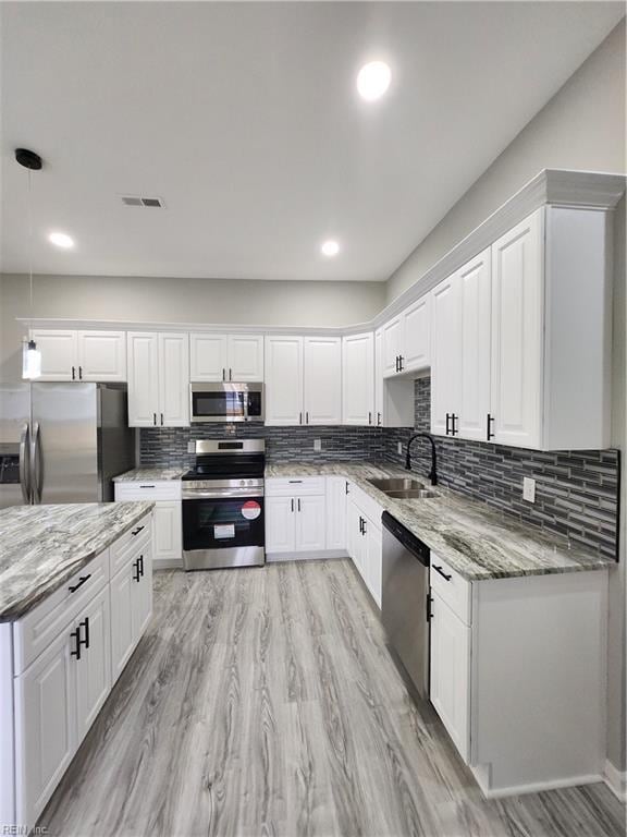 kitchen with sink, white cabinetry, stainless steel appliances, and hanging light fixtures