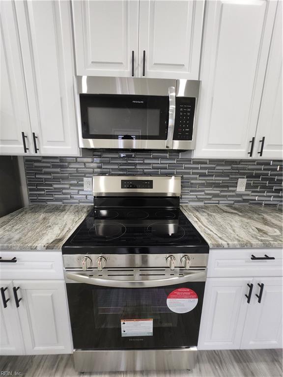 kitchen featuring light stone countertops, white cabinets, and stainless steel appliances