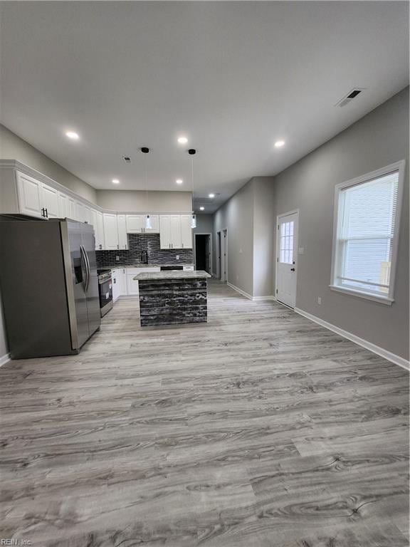 kitchen featuring a center island, stainless steel appliances, light hardwood / wood-style floors, decorative light fixtures, and white cabinets