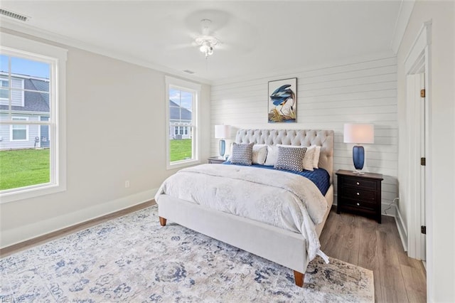 bedroom featuring multiple windows, light hardwood / wood-style flooring, ceiling fan, and crown molding