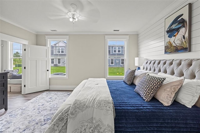 bedroom featuring multiple windows, hardwood / wood-style flooring, ceiling fan, and crown molding