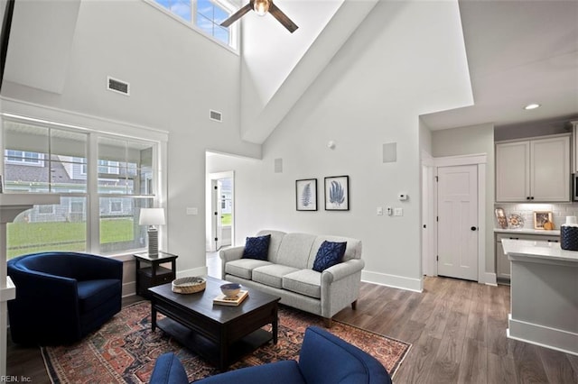 living room featuring ceiling fan, hardwood / wood-style floors, and a towering ceiling