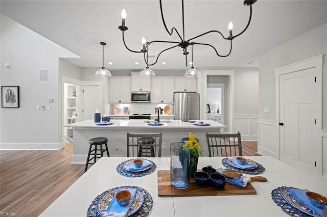 dining space featuring light wood-type flooring, sink, and a chandelier