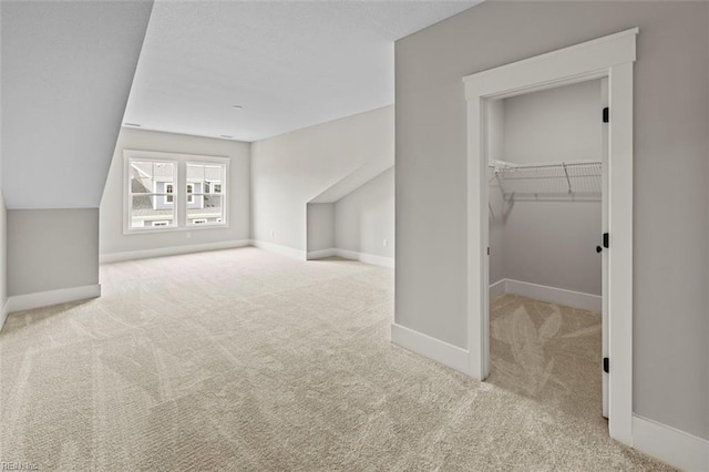 additional living space featuring light colored carpet and lofted ceiling