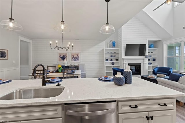 kitchen featuring dishwasher, pendant lighting, light stone counters, and sink