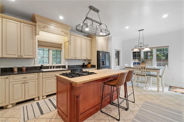 kitchen with stainless steel appliances, sink, cream cabinets, a kitchen island, and hanging light fixtures