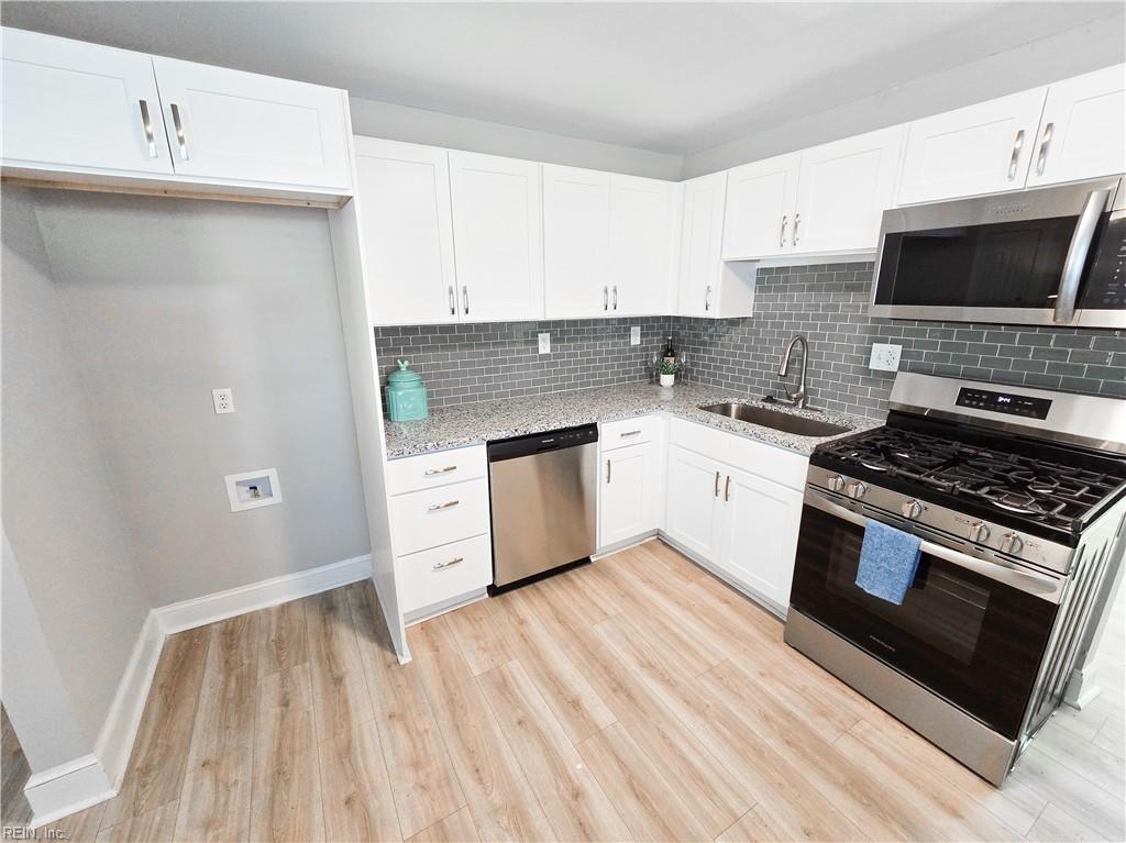 kitchen featuring sink, light stone countertops, light hardwood / wood-style floors, white cabinetry, and stainless steel appliances