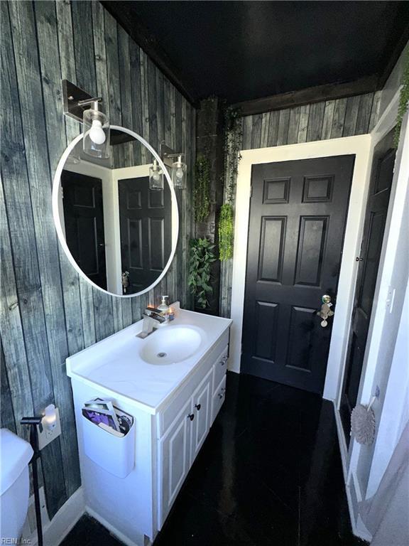 bathroom featuring wooden walls, vanity, and toilet