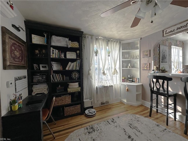 interior space with a textured ceiling, light hardwood / wood-style floors, and ceiling fan