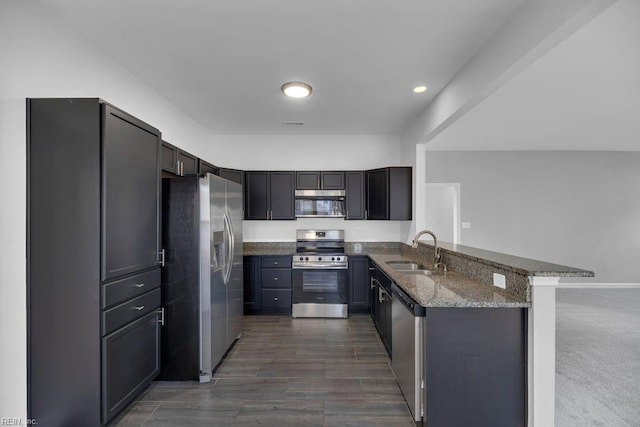 kitchen with stone countertops, sink, kitchen peninsula, and stainless steel appliances