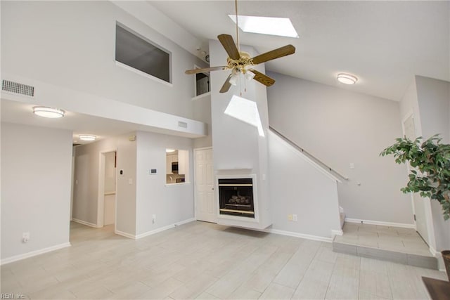 unfurnished living room featuring ceiling fan, high vaulted ceiling, and a skylight