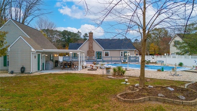 back of house featuring a lawn, a patio, and a covered pool