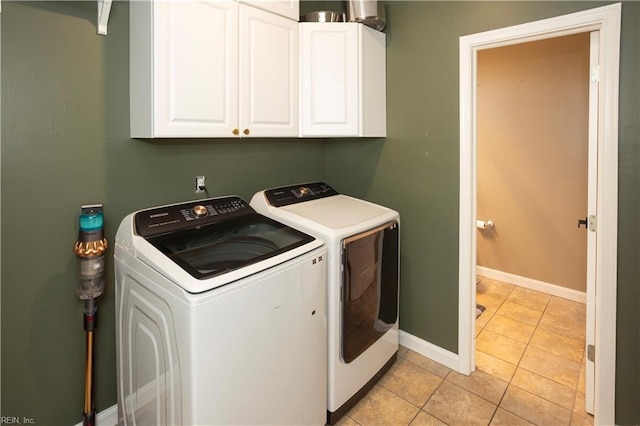 laundry area featuring cabinets, light tile patterned floors, and washing machine and clothes dryer