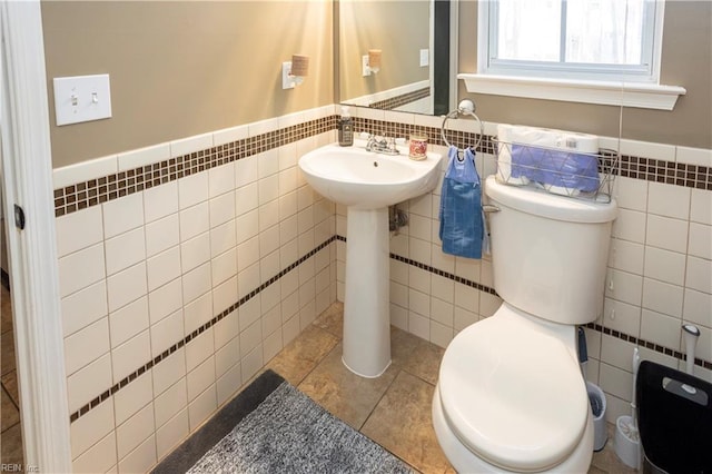 bathroom featuring tile patterned floors, toilet, and tile walls