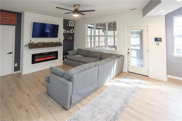 living room featuring ceiling fan, a fireplace, and light hardwood / wood-style flooring