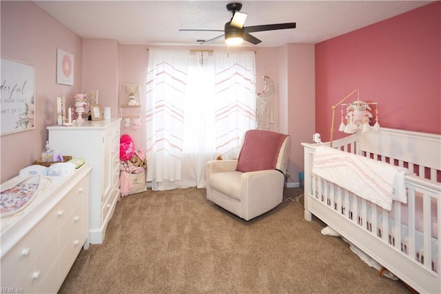 carpeted bedroom featuring ceiling fan and a crib