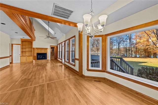 unfurnished living room with lofted ceiling with beams, ceiling fan with notable chandelier, and light hardwood / wood-style floors