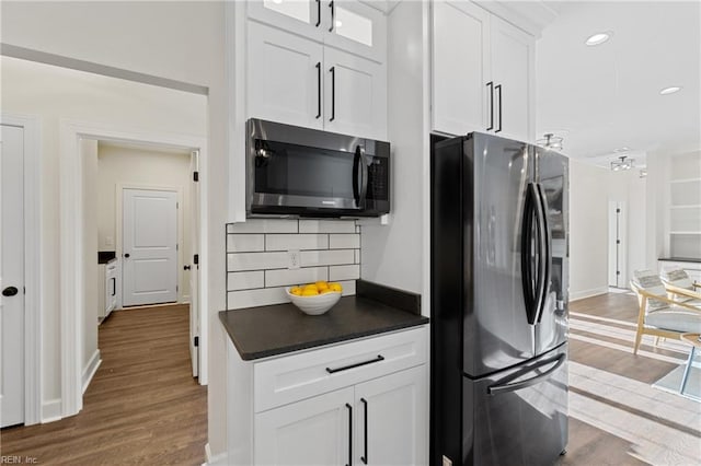 kitchen featuring hardwood / wood-style flooring, white cabinetry, backsplash, and appliances with stainless steel finishes