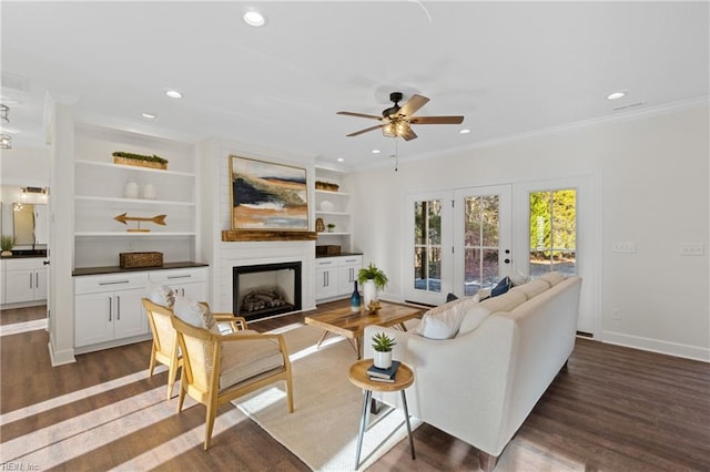 living room with built in shelves, ceiling fan, french doors, dark hardwood / wood-style floors, and ornamental molding