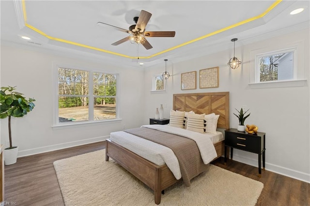 bedroom featuring dark hardwood / wood-style flooring, a raised ceiling, ceiling fan, and ornamental molding