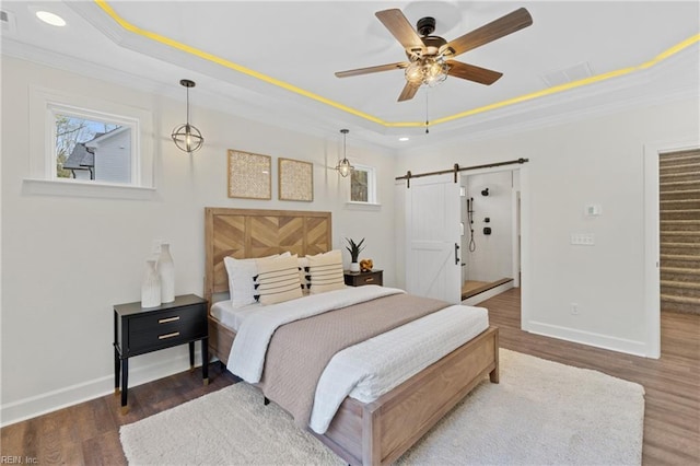 bedroom with a barn door, a raised ceiling, ceiling fan, and ornamental molding