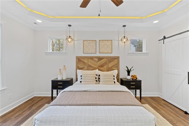 bedroom featuring a raised ceiling, a barn door, and ornamental molding