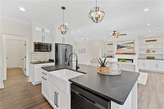 kitchen featuring sink, hanging light fixtures, stainless steel appliances, an island with sink, and white cabinets