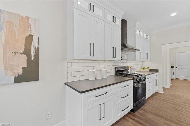 kitchen featuring black gas range, white cabinetry, wall chimney range hood, dark hardwood / wood-style floors, and decorative backsplash