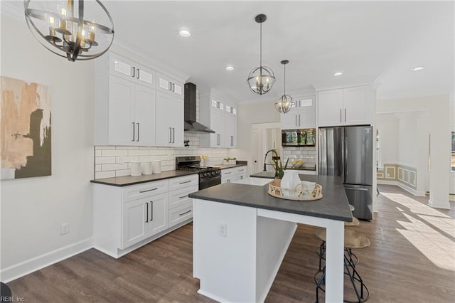 kitchen with appliances with stainless steel finishes, white cabinetry, pendant lighting, and wall chimney range hood