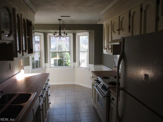 kitchen featuring stainless steel electric range oven, an inviting chandelier, crown molding, fridge, and light tile patterned floors