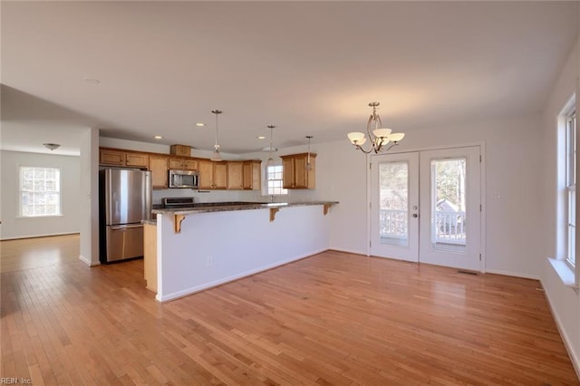 kitchen with french doors, a kitchen breakfast bar, plenty of natural light, pendant lighting, and appliances with stainless steel finishes