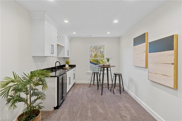 kitchen featuring wine cooler, white cabinetry, sink, and light colored carpet