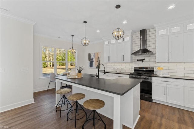 kitchen with white cabinets, stainless steel gas range oven, wall chimney exhaust hood, and sink