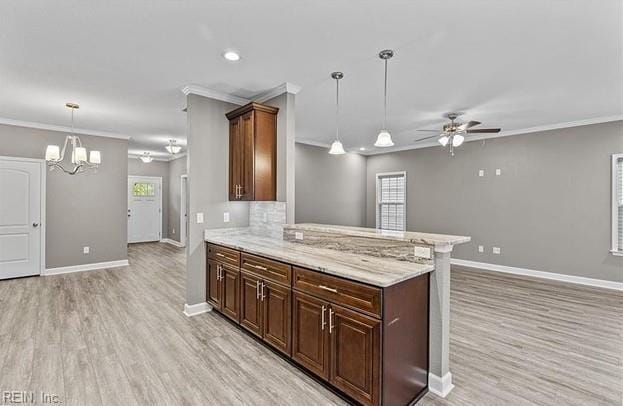 kitchen with kitchen peninsula, crown molding, pendant lighting, ceiling fan with notable chandelier, and light wood-type flooring