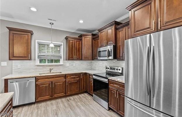 kitchen with appliances with stainless steel finishes, backsplash, sink, light hardwood / wood-style floors, and hanging light fixtures