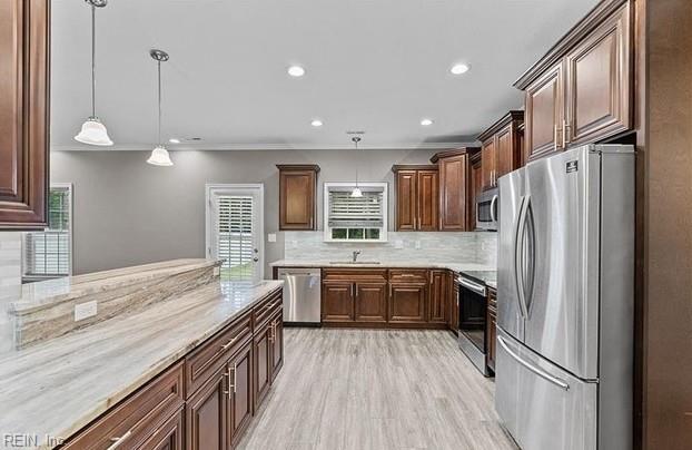 kitchen with sink, stainless steel appliances, backsplash, light hardwood / wood-style floors, and pendant lighting