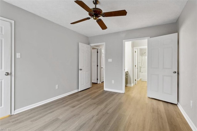 unfurnished bedroom featuring ensuite bath, ceiling fan, and light wood-type flooring